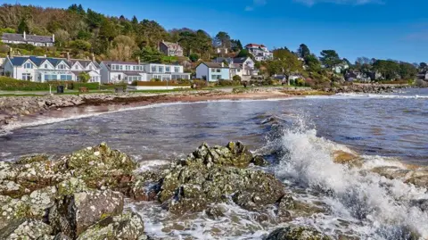 Getty Images The village of Rockcliffe on the Solway Coast with waves crashing into the shore in front of a row of picturesque houses looking out into the bay