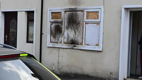 A house with windows boarded up after an arson attack.
