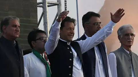 Getty Images Pakistan's Prime Minister Imran Khan (C) along with other lawmakers, gestures upon his arrival to address the supporters of ruling Pakistan Tehreek-e-Insaf (PTI) party during a rally in Islamabad on March 27, 2022.