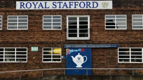 BBC The brick building has many windows and a blue Royal Stafford sign with logo lower down at ground level.