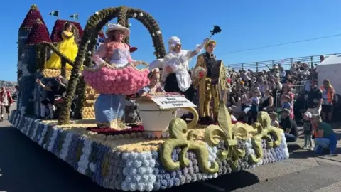 BBC Crowds cheer the Parish of St Helier's float in last year's parade