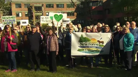 Crowds of people stood with signs outside the New Forest District Council offices.