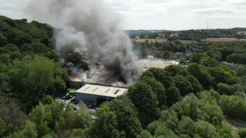Large plumes of grey and black smoke emerge from an industrial building.
