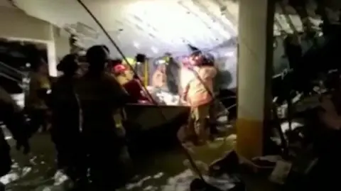 firefighters search through rubble