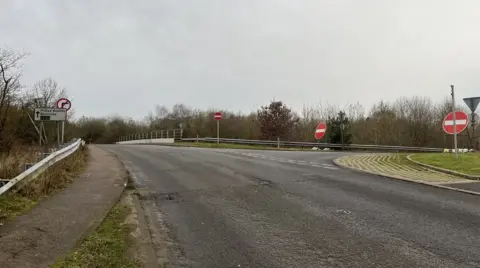 BBC/Tony Fisher A picture of a bridge over the A5, showing a slip road on the right hand side of the picture. At the entrance to the slip road there are two "no entry" signs, to try to stop drivers going down it the wrong way.