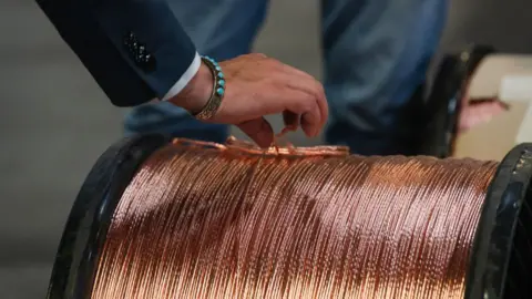 Getty Images The hand of Representative Gabe Vasquez, a Democrat from New Mexico wearing a turquoise bracelet, inspects copper wire during a tour of CN Wire Corporation in Santa Teresa, New Mexico, US, on Wednesday, Feb. 21, 2024. 