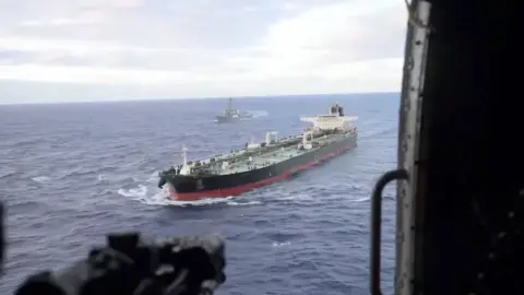 Oil tanker in ocean as seen from a helicopter door