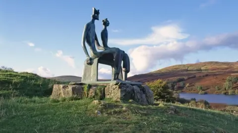 Alamy The King and Queen sculpture viewed from another angle with trees and fields behind it