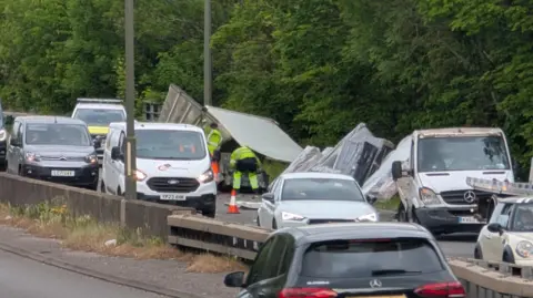 The aftermath of a collision involving a lorry on the A52, with traffic now passing the scene