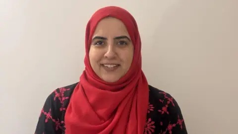 Lady wearing a red hijab and black and red dress.