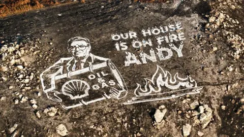 Greenpeace A Greenpeace mural Andy Burnham in white paint on a scorched hillside