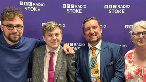 Painsley Catholic College From left - Lee Blakeman, William Simpson, Adam Reynolds and Tracey Simpson. A group of for men and one woman stand in a row smiling at the camera against a purple background with BBC Radio Stoke logos
