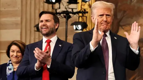 Amy Kobuchar smiles, JD Vance claps and Donald Trump gestures during the inauguration