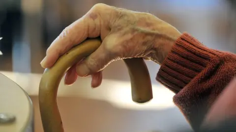 BBC Elderly person holding walking stick