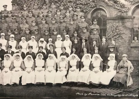University of Cumbria A black and white image with seven rows of soldiers and nurses posing for a photo outside Skiddaw House in Carlisle. The men are all in military uniform, with the nurses wearing white nursing gowns and headwear.