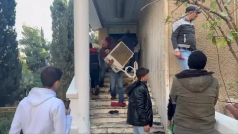 People exiting residential house with radiator in their hands