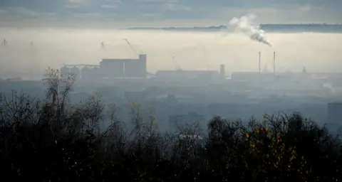 A long-range image shows a thick layer of fog sitting over Belfast city