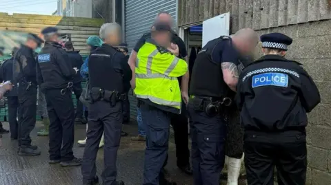 Home Office Immigration staff, joined by police, are questioning people outside a business premises