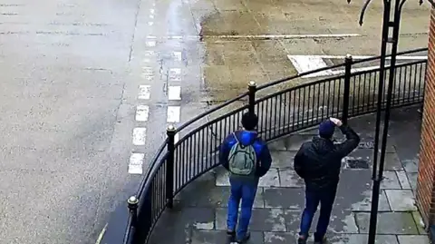 Metropolitan Police CCTV showing two men on a street corner in Salisbury, showing their backs, one wearing a grey rucksack. 