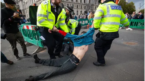 PA Media Police officers removing a demonstrator