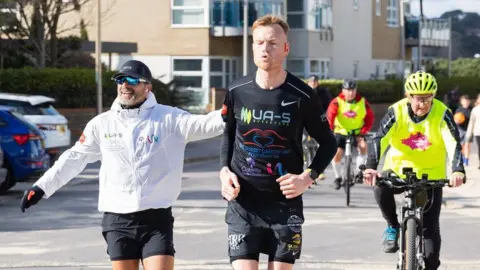 Debbie Granville PR Chris Helberg running with Rich Bryer-Ash. The pair are being followed by people on bicycles.