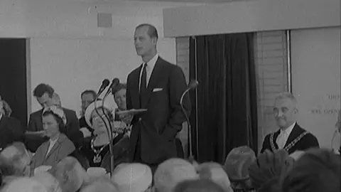 British Pathe Black and white footage of Prince Philip opening the terminal. He stands in front of a crowd reading a speech. 