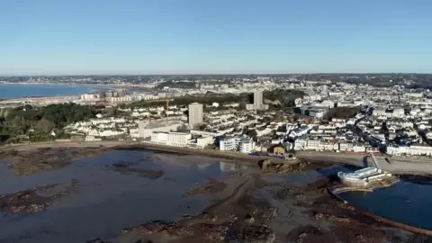 A drone photo of Jersey with some of the island's water on the bottom half of the photo