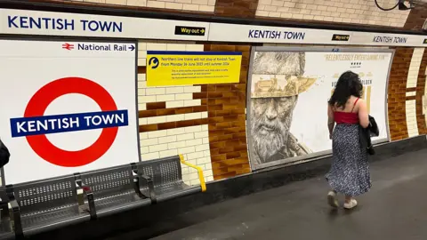 Kentish Town station platform showing roundel and woman walking past a sign warning of the closure