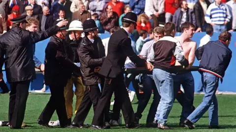 Getty Images Policemen rescue soccer fans