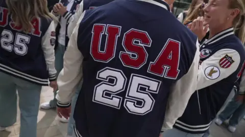 Team USA arrive with jersey's saying 'USA 25' on the back of them in red and white against a background of navy.