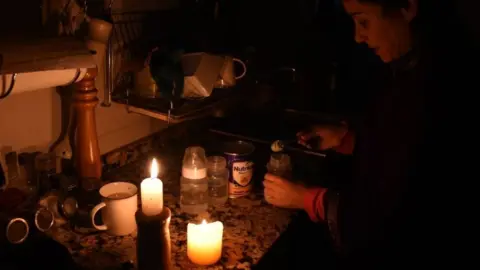 AFP A woman works by candle in her kitchen during a blackout in Uruguay