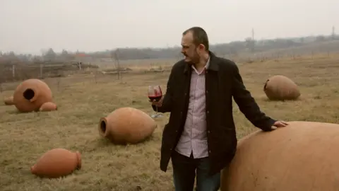 Nanka Dolidze Koka Archvadze sits on a qvevri