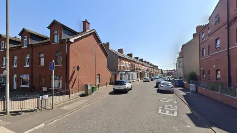 Google Maps A Google Maps street view of Eia Street in north Belfast. There are a number of cars parked on either side of the street. The street shows a number of red brick, terrace houses with red brick buildings on either side of the street's opening.