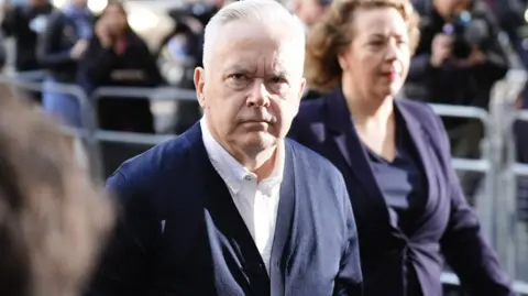 PA Media A man with grey hair, tanned skin, wearing a white shirt and blue jacket