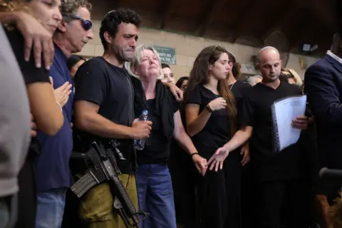 y ABIR SULTAN/EPA-EFE/REX/Shutterstock Kim Damti's family console each other during her funeral