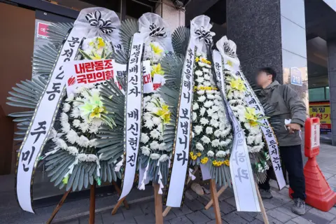 News1 Funeral flowers - large floral displays with banners - are seen outside a building