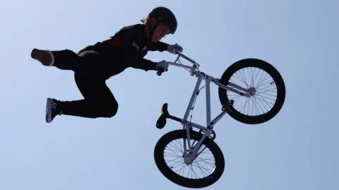 Reuters Reilly in black holding onto the handlebars of his airborne bike