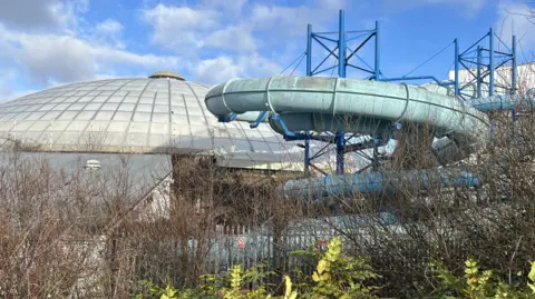 The dome of Oasis and one of the domebuster slides disused surrounded by overgrown vegetation
