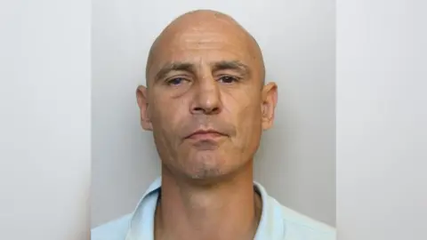 Avon and Somerset Police Daniel Russell mugshot. He has a bald head and is cleanly shaven
