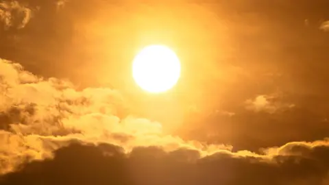 The sun in the sky with some clouds 