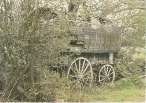 Walsall Archive A dilapidated Gypsy caravan stands amid grass and trees with wooden slats on its roof missing