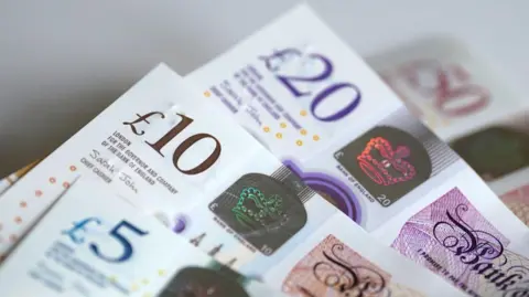 A close up of banknotes with the Crown embossed on a hologram security feature.
