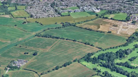 Open fields with housing to the north viewed from above via satellite imagery - Google Earth