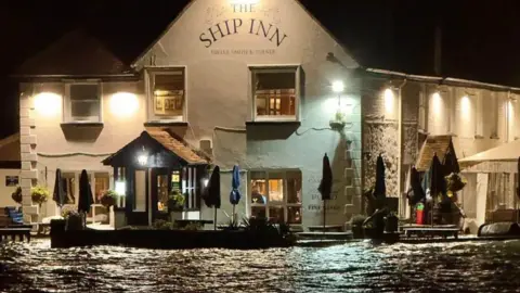 Ben Harmer The Ship Inn at Langstone, Havant, flooded in the early hours. It is dark but lights at the top of the building allow to see its name. 