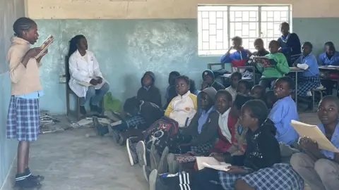 BBC A pupil standing at the front of the class reading something out