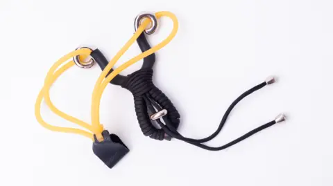 Getty Images A black and yellow catapult lying on a plain white surface.