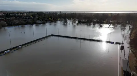 A flooded football pitch surrounded by floodwater and trees, with the River Severn noticeable in the background