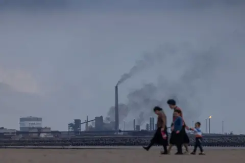 Getty Images People walking in front of the steelworks in Port Talbot 