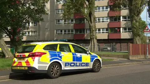 A police car parked on a street outside a block of flats.