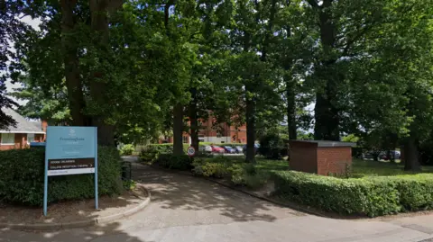 Google A general view of the entrance into Framlingham College. A blue sign reads the school's name and trees are lined outside the school's main front building.
